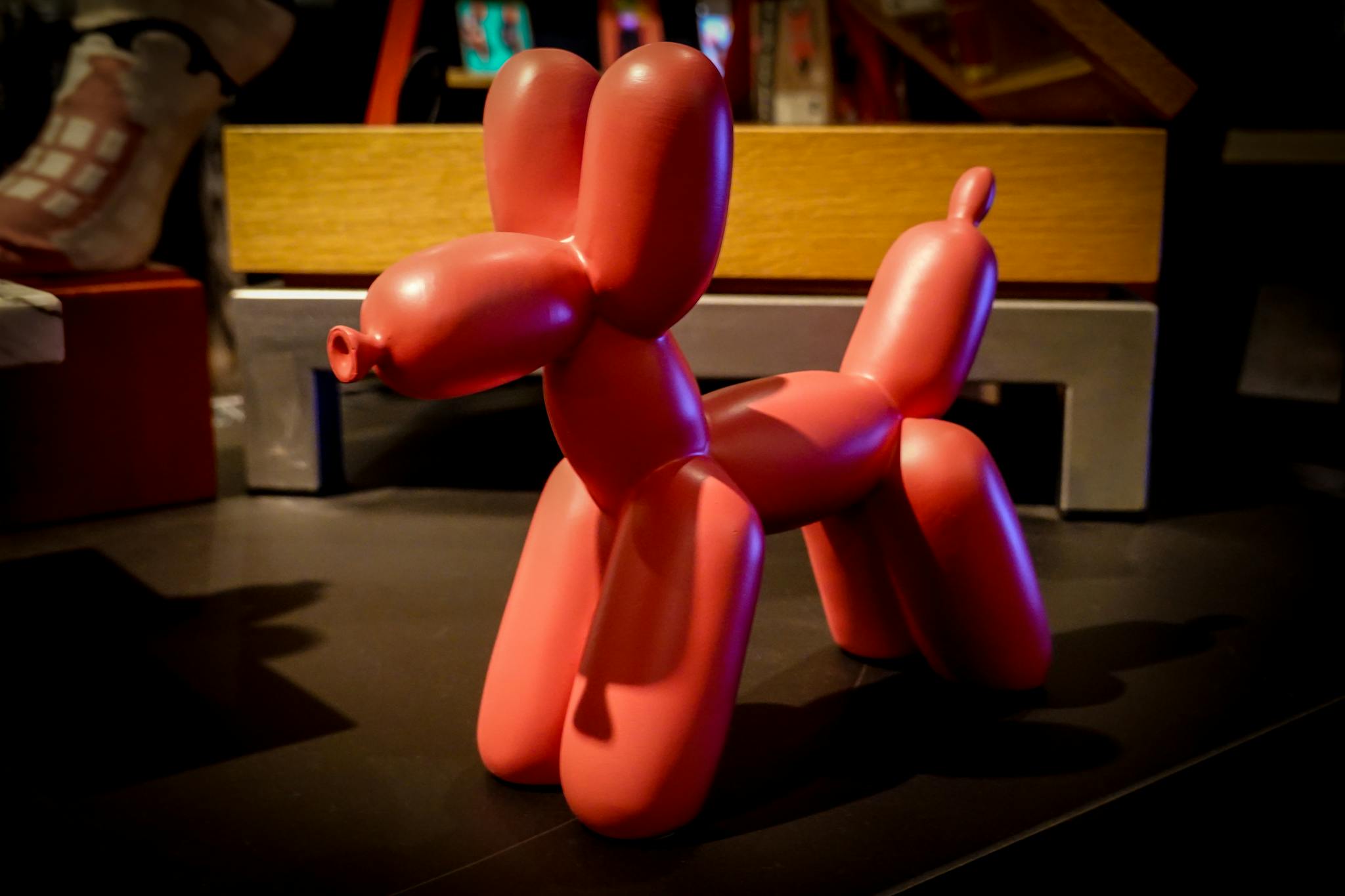 Vibrant red balloon dog sculpture creatively displayed in a modern store setting.